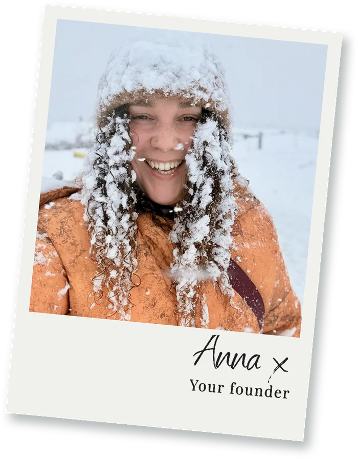 Polaroid of Anna grinning with snow in her hair and a copper coat, signed Anna x, your founder